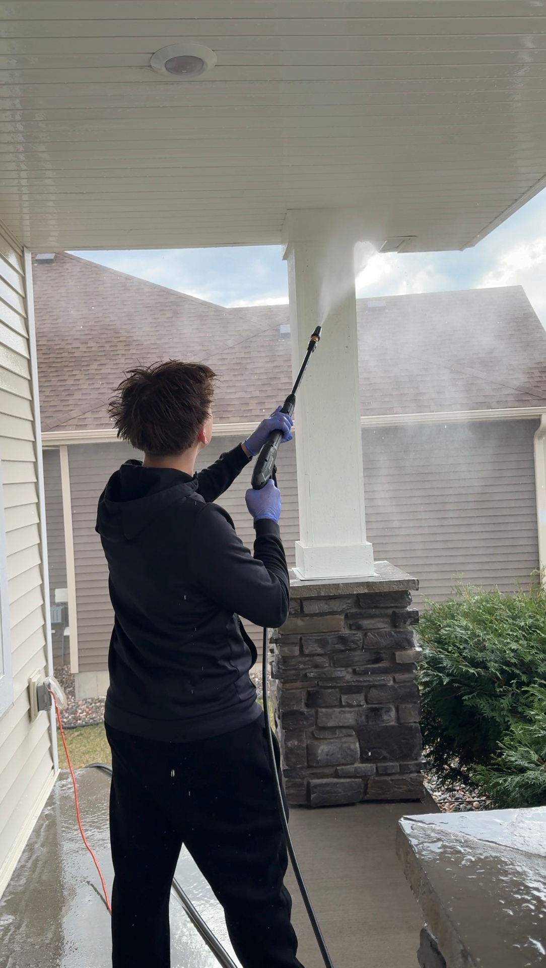 Brecken pressure washing a porch column